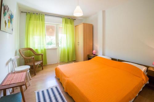 Schlafzimmer mit orangefarbenem Bett und grünen Vorhängen in der Unterkunft Studio Apartman Filipa in Jadranovo