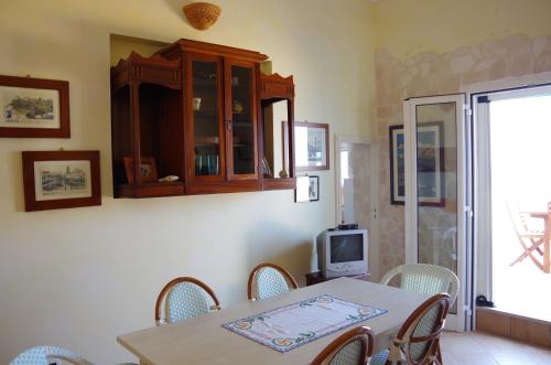 a dining room with a table and chairs and a tv at Terrazza sul mare in Villanova di Ostuni