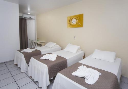 three beds in a hotel room with towels on them at Hotel Rekinte in Aracaju