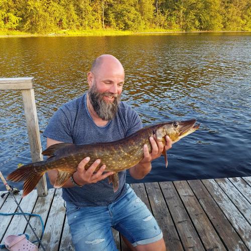 a man holding a fish in his hands on a dock at Furuliden Country Inn in Vittsjö