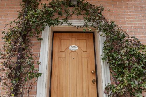 a wooden door in a brick building with ivy at Camere La Basilica in Assisi