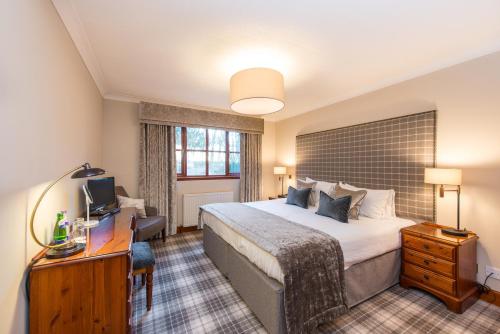 a hotel room with a large bed and a desk at Murrayshall Country Estate in Perth