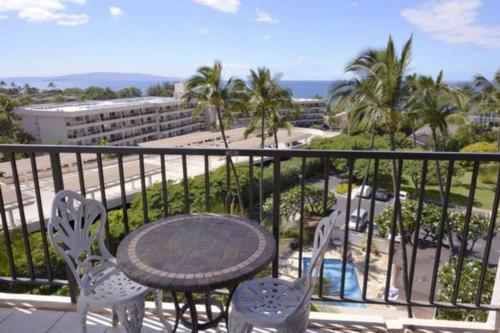 a balcony with a table and chairs and a view of the ocean at Kihei Akahi in Wailea