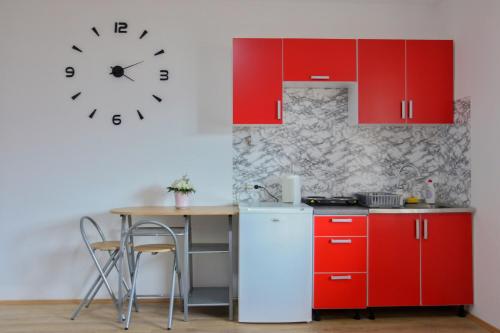 a kitchen with red cabinets and a clock on the wall at Sobe Mira in Trebinje