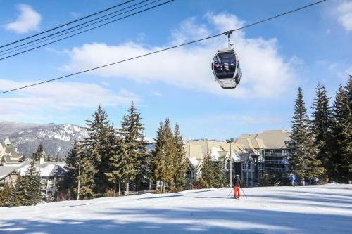 a person riding a ski lift on a snow covered slope at The Woodrun Lodge by Whiski Jack in Whistler