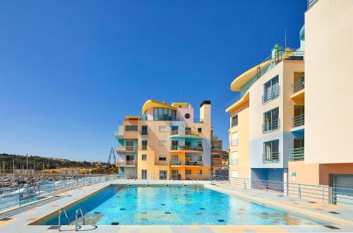 a swimming pool in front of two buildings at Casas Barulho Albufeira Marina in Albufeira