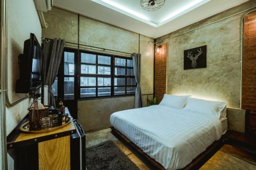 a bedroom with a bed and a tv and a window at Zeds Hostel Bangkok in Bangkok