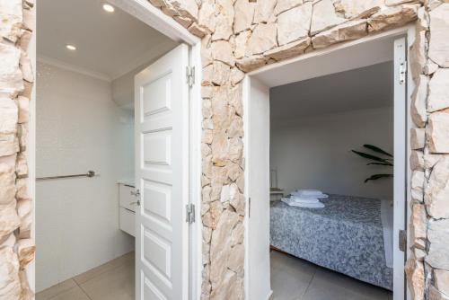 Habitación con pared de piedra y puerta que conduce a un dormitorio. en Fisherman's Beach Home 2BR 2BA AC Wi-Fi en Albufeira