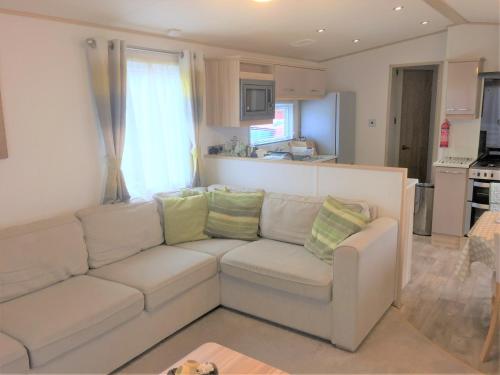 sala de estar con sofá blanco y cocina en Honeydukes Holiday Lodge, Boat of Garten, Aviemore, en Boat of Garten