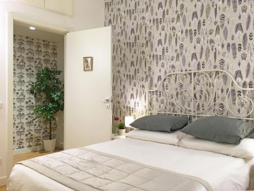 sypialnia z białym łóżkiem i wzorzystą ścianą w obiekcie M SuiteApartment Roma w Rzymie