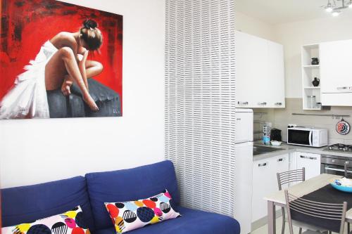 a living room with a blue couch and a painting of a woman at Holiday Home Arzilli in Follonica