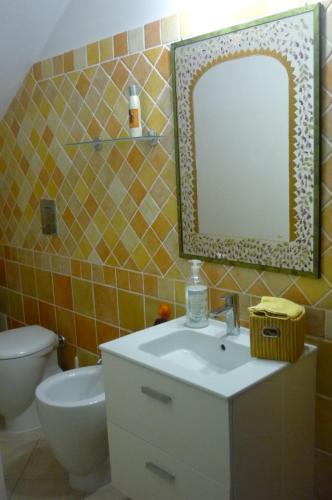bagno con lavandino, specchio e servizi igienici di Ampia e graziosa Casa Vacanza a Pula