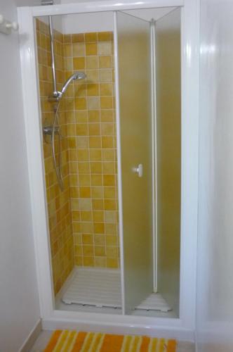 una doccia con porta in vetro e piastrelle gialle di Ampia e graziosa Casa Vacanza a Pula