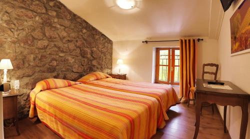 um quarto com uma cama e uma parede de pedra em Hostellerie du Vieux Moulin em Duilhac