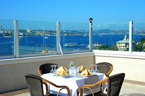 Askoc Hotel & SPA في إسطنبول: طاولة مع كراسي وإطلالة على الماء
