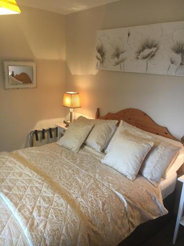 una camera da letto con letto, lenzuola e cuscini bianchi di St. Catherines a Doolin