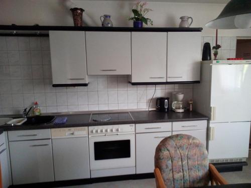 a kitchen with white cabinets and a white refrigerator at Hotel Seehaus in Horn-Bad Meinberg