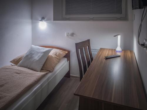 um quarto com uma cama e uma mesa de madeira com um candeeiro em Pension Palla em Svojanov