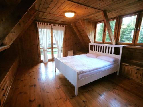 sypialnia z białym łóżkiem na poddaszu w obiekcie EKOEDEN - OŚRODEK WYPOCZYNKOWY w mieście Połczyn-Zdrój