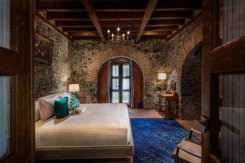 a bedroom with a large bed with a blue rug at Hacienda Santo Cristo Hotel & Spa - Adults Only in Atlixco
