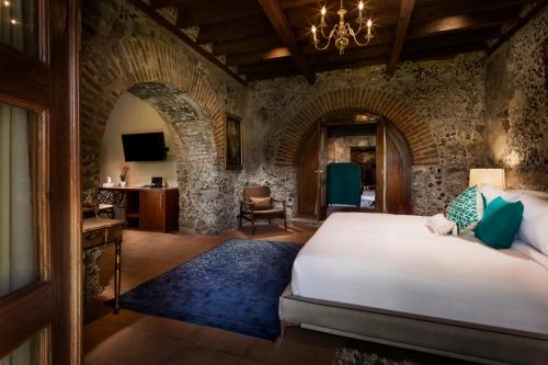 a bedroom with a bed and a stone wall at Hacienda Santo Cristo Hotel & Spa - Adults Only in Atlixco