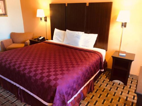 HopeにあるAmericas Best Value Inn and Suites Hopeの大きなベッドと椅子が備わるホテルルームです。