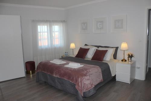 a bedroom with a large bed with two lamps at Vigia's Guest House in Viseu