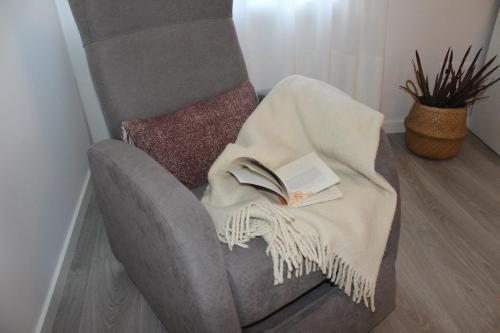 una coperta su una sedia con un libro sopra. di Vigia's Guest House a Viseu