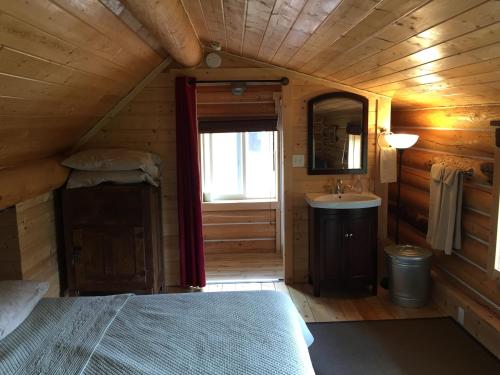 a bedroom with a bed and a sink in a room at Cabins Over Crag Lake in Carcross