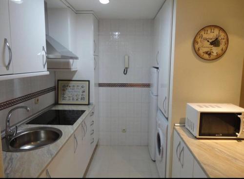 Una cocina con un fregadero y un reloj en la pared. en Corrillo Suite Plaza Mayor - Parking opcional, en Salamanca