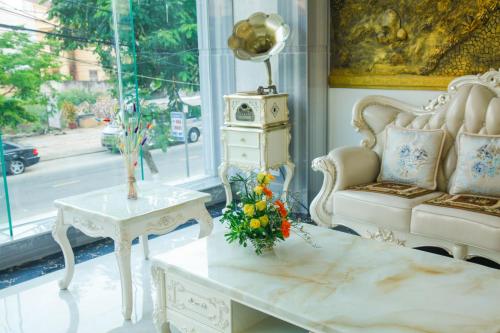 a living room with a couch and a table with flowers on it at Golden Rose Hotel in Da Nang