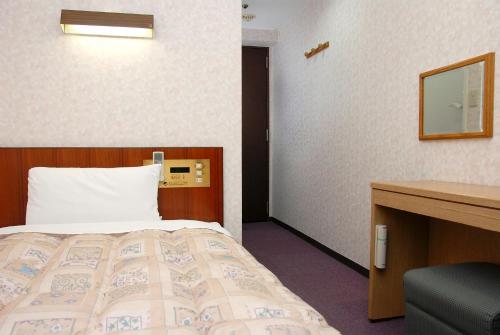 a hotel room with a bed and a desk at Hotel New Plaza Kurume in Kurume