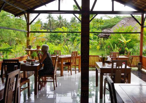 a woman sitting at a table in a restaurant at Budi Sun Resort, Flores, Maumere in Maumere