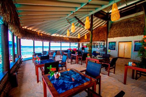 ein Restaurant am Strand mit Tischen und Stühlen in der Unterkunft Manuia Beach Resort in Rarotonga