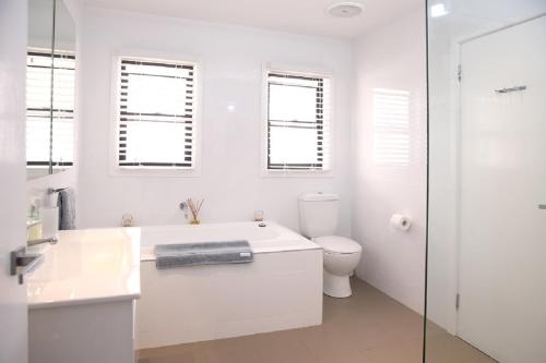 a white bathroom with a tub and a toilet at Refuge Cove On Pittwater in Clareville