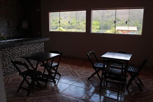 2 tafels en stoelen in een kamer met een raam bij Espaço Ecológico e Pousada Terra Betania in São João da Aliança