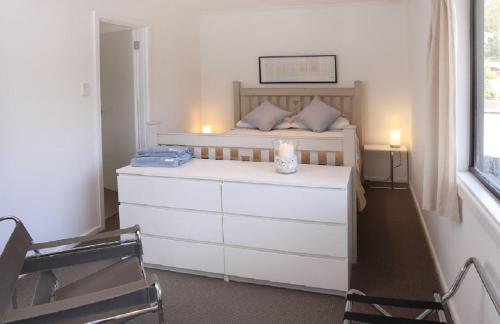 a bedroom with a bed and a dresser with a candle on it at Refuge Cove On Pittwater in Clareville