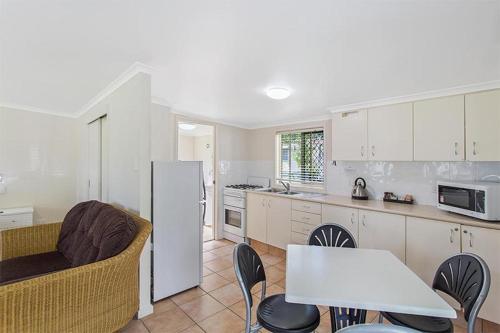 a kitchen with a white refrigerator and a table and chairs at Landsborough Holiday Park in Landsborough