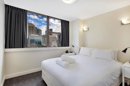 シドニーにあるPark View Apartmentの白い大型ベッド1台と窓が備わるホテルルームです。