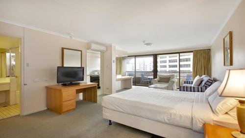 a hotel room with a bed and a television at Studio with balcony at College St in Sydney