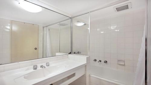 a white bathroom with a sink and a mirror at Studio with balcony at College St in Sydney