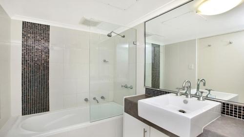 a white bathroom with a sink and a shower at In the City Studio at College St in Sydney