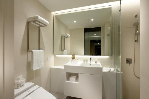 a bathroom with a sink and a toilet and a mirror at The Place Taipei in Taipei