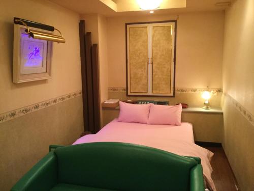 a small room with a bed and a green chair at Dear Place(Adult Only) in Osaka