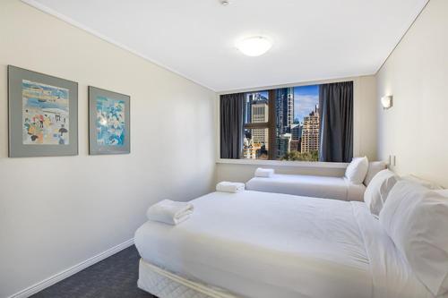 een witte kamer met 2 bedden en een raam bij Apartment at College St in Sydney