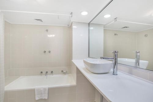 a bathroom with a sink and a tub and a mirror at Apartment at College St in Sydney