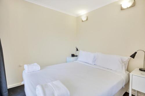 een wit bed met witte kussens in een slaapkamer bij City apartment at College St in Sydney