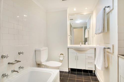 a white bathroom with a tub and a sink at Apartment Harborside Comfort in Sydney