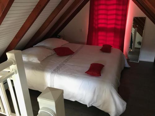 1 dormitorio con 1 cama blanca grande con almohadas rojas en Iguane Rouge, en Petit-Bourg