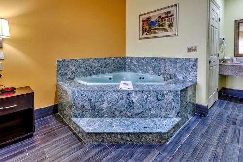La salle de bains est pourvue d'une grande baignoire et de parquet. dans l'établissement Quality Inn, à Brownsville
